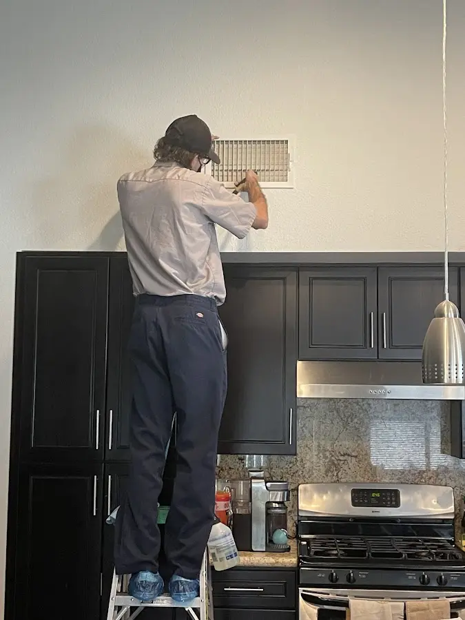 Technician inspecting an air vent during HVAC service in California